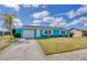 Charming turquoise home featuring a white garage door, front door, white trimmed windows, and a manicured front lawn at 6264 Drucker Cir, Port Charlotte, FL 33981