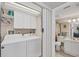 Laundry area with a white washer and dryer, overhead cabinets, and a view into the bathroom at 6699 San Casa Dr # Q3, Englewood, FL 34224
