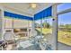 Bright sunroom featuring white wicker furniture, blue and floral valances, and serene views of the outdoors at 6699 San Casa Dr # Q3, Englewood, FL 34224