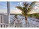 Gorgeous view of the beach with a path from the stairs with lush green palms and warm sunset in the distance at 7430 Palm Island Dr # 3813, Placida, FL 33946