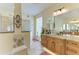 Bathroom with a double vanity featuring granite countertops, decorative accents, and a tiled shower at 8264 Antwerp Cir, Port Charlotte, FL 33981