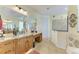 Bright bathroom featuring a wooden vanity with granite countertops, a decorative mirror, and tiled walk-in shower at 8264 Antwerp Cir, Port Charlotte, FL 33981