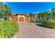 Lovely home featuring a three-car garage, terracotta roof, lush landscaping, and a brick driveway at 8264 Antwerp Cir, Port Charlotte, FL 33981