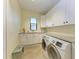 This laundry room is equipped with modern washer and dryer, bright cabinets, and granite countertops at 8264 Antwerp Cir, Port Charlotte, FL 33981