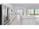 Bright, white kitchen with stainless steel appliances and a large center island with a sink overlooking water view at 8562 Shore Lake Dr, Englewood, FL 34224