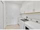 Bright laundry room with washer, dryer, sink and storage cabinets at 8562 Shore Lake Dr, Englewood, FL 34224
