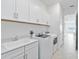 Bright laundry room with washer, dryer, sink and storage cabinets at 8562 Shore Lake Dr, Englewood, FL 34224