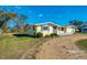 Angle view of a light yellow single-story home, showcasing the front and side yards at 91 Beverly Cir, Englewood, FL 34223