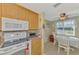 Bright kitchen features wooden cabinets, white appliances, tile backsplash, and eat in dining area with natural light at 91 Beverly Cir, Englewood, FL 34223