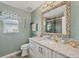 The bathroom has a seashell mirror, a vanity with granite countertops, and a sliding glass shower door at 9460 Migue Cir, Port Charlotte, FL 33981