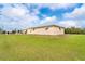 Expansive backyard featuring a sparkling pool, manicured lawn, and property exterior with secure jalousie windows at 10075 Bentley Ave, Englewood, FL 34224