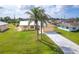 Charming home with a well-manicured front lawn, palm trees, and a long driveway leading to an attached garage at 10075 Bentley Ave, Englewood, FL 34224