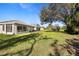 Lush backyard with expansive lawn, mature trees, and lanai of the house at 1332 Hedgewood Cir, North Port, FL 34288