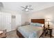 Bedroom with a queen bed, fan, and side table with lamp, plus a view of two doors at 1332 Hedgewood Cir, North Port, FL 34288