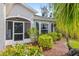 Inviting front entrance with a screened porch, lush landscaping, and well-maintained flowerbeds at 1332 Hedgewood Cir, North Port, FL 34288