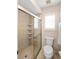 Bathroom featuring a glass-enclosed shower, toilet, shuttered window, and neutral tiling at 1332 Hedgewood Cir, North Port, FL 34288