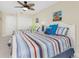 Bright bedroom featuring two beds with striped linens, beach-themed decor, and a ceiling fan at 1410 Beach Rd # 201, Englewood, FL 34223
