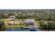Expansive aerial view of canal-front house featuring a private dock, boat, and landscaped backyard; residential area beyond at 14382 Lillian Cir, Port Charlotte, FL 33981