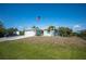 Charming single-story home featuring a two-car garage, palm trees, and a manicured lawn under a clear blue sky at 14382 Lillian Cir, Port Charlotte, FL 33981
