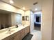 Well-lit bathroom featuring a double vanity, a large mirror, and a view into the bedroom at 14399 Morristown Ave, Port Charlotte, FL 33981