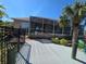 Screened-in patio with a view of a palm tree and a canal, surrounded by a black fence and green plants at 14970 Appleton Blvd, Port Charlotte, FL 33981