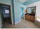 Large bathroom with blue walls and tiled flooring leads into a toilet room and a bedroom at 14970 Appleton Blvd, Port Charlotte, FL 33981