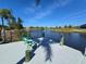 Waterfront dock with chairs overlooking canal with reeds and neighboring houses on a sunny day at 14970 Appleton Blvd, Port Charlotte, FL 33981