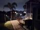 A night view of a home's patio and garden area with lights, pavers, and canal at 14970 Appleton Blvd, Port Charlotte, FL 33981