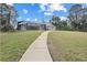 Backyard view of a home with pool and screened-in lanai accessible by concrete path at 150 N Oxford Dr, Englewood, FL 34223
