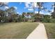 A concrete walkway through a landscaped yard with mature palm trees at 150 N Oxford Dr, Englewood, FL 34223