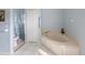 Bathroom featuring a large soaking tub, tile floors, and a commode at 150 N Oxford Dr, Englewood, FL 34223