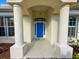 A welcoming front entrance with a vibrant blue door flanked by elegant white columns and lush greenery at 150 N Oxford Dr, Englewood, FL 34223