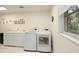 Functional laundry room with modern washer and dryer, ample counter space, and natural light from a window at 150 N Oxford Dr, Englewood, FL 34223
