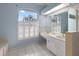 The main bathroom features dual sinks, white cabinetry, and a large window with plantation shutters at 150 N Oxford Dr, Englewood, FL 34223