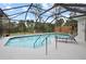 Enclosed swimming pool with a lounge chair, ladder and view of mature palm trees at 150 N Oxford Dr, Englewood, FL 34223
