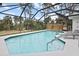 Screened pool with blue tile trim and surrounding palm trees in a tropical backyard setting at 150 N Oxford Dr, Englewood, FL 34223