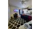 Well-lit bedroom with a ceiling fan, TV, and black and white patterned rug at 15408 Feather Star Pl, Ruskin, FL 33573