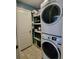 Convenient laundry room area featuring a stacked washer and dryer and shelving for storage at 15408 Feather Star Pl, Ruskin, FL 33573