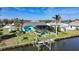 Waterfront home featuring a boat lift, lush landscaping, and a screened-in pool area at 15652 Ruston Cir, Port Charlotte, FL 33981