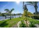 Waterfront backyard featuring well-manicured lawn, decorative garden, and access to a serene canal waterway at 15652 Ruston Cir, Port Charlotte, FL 33981