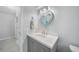 A bright bathroom with light gray wood floors, a sink vanity, and a heart shaped mirror at 15652 Ruston Cir, Port Charlotte, FL 33981