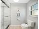 A bright bathroom with a marble glass shower, white toilet, wood floors, and small built in shelving at 15652 Ruston Cir, Port Charlotte, FL 33981