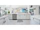 Bright, open kitchen with white cabinets, stainless appliances, bar seating, and view of the living room at 15652 Ruston Cir, Port Charlotte, FL 33981