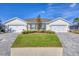 Charming home featuring a well-manicured lawn, elegant paver driveway, and symmetrical facade at 16273 Coconut Palm Dr, Port Charlotte, FL 33953