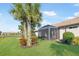 Beautiful backyard with a screened-in lanai, lush green lawn, tropical plants, and a tranquil lake view at 19241 Serafina St, Venice, FL 34293