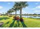 Lush backyard with a tranquil lake, manicured lawn, and tropical landscaping creating a serene outdoor space at 19241 Serafina St, Venice, FL 34293