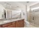 Well-lit bathroom with double sinks, granite countertops, tiled shower with glass door, and tile floors at 19241 Serafina St, Venice, FL 34293