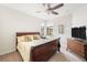Bright bedroom featuring a wood bed, ceiling fan, dresser, and a scenic view from the large window at 19241 Serafina St, Venice, FL 34293