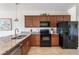 Functional kitchen featuring stainless steel appliances, granite countertops, and tile flooring for easy maintenance at 19241 Serafina St, Venice, FL 34293