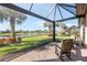 Relaxing screened-in lanai with brick floor and rocking chairs overlooks a serene lake and tropical landscaping at 19241 Serafina St, Venice, FL 34293